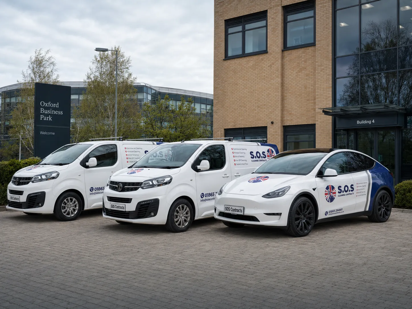 The SOS Cleaning Contracts fleet — two branded vans and a Tesla — parked outside Building 4, Oxford Business Park